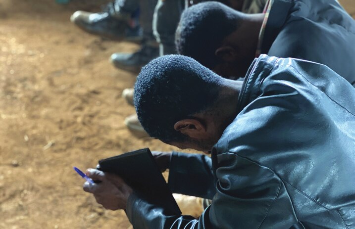 Man bowed in prayer with notebook
